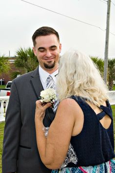 a man in a suit and tie standing next to a blonde haired woman wearing a flower bouquet