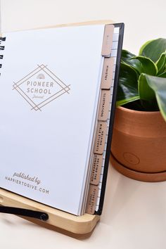 a note book sitting on top of a wooden stand next to a potted plant