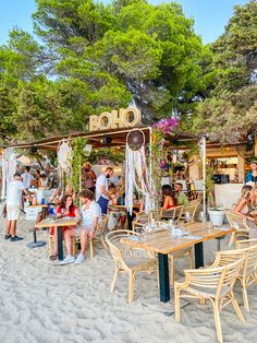 many people are sitting at tables on the beach