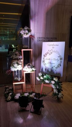 flowers are arranged on wooden stands in front of a sign