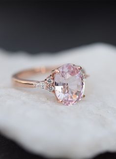 a pink diamond ring sitting on top of a white cloth