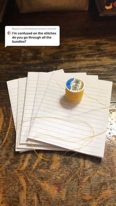 three sheets of lined paper sitting on top of each other next to a spool of thread