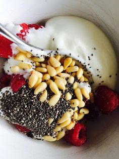 a bowl filled with cereal and yogurt next to raspberries