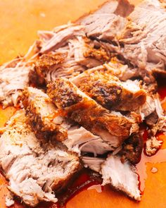 sliced meat sitting on top of a cutting board covered in ketchup and sauce