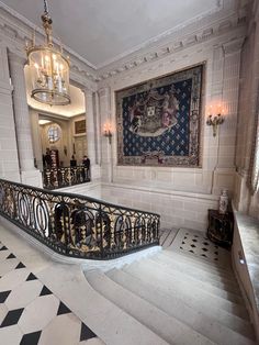 an ornate staircase with chandelier and rug on the wall in a white room