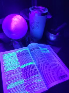 an open book sitting on top of a table next to a purple ball and cup