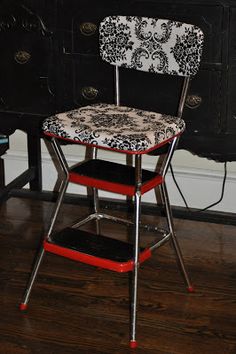 a red and white chair sitting on top of a wooden floor next to a black dresser