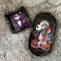 two black trays with halloween designs on them sitting on a gray carpet next to each other