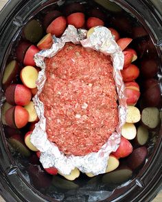 an open crock pot filled with meat, potatoes and carrots on top of tin foil