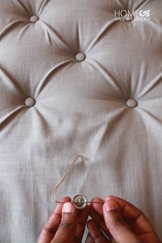 two hands are holding something in front of a button on a bed headboard that has buttons attached to it