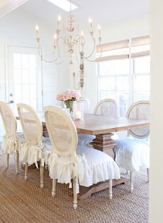 a dining room table with white chairs and a chandelier