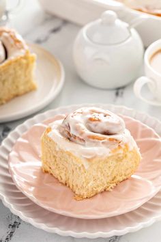 there is a piece of cake on the plate with icing and coffee in the background