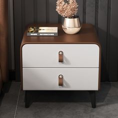 a white and brown nightstand with flowers on it next to a black wall in a room