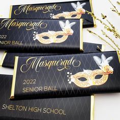 four black and gold masquerade name tags on a table