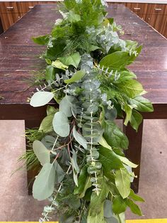 a wooden table topped with lots of green plants