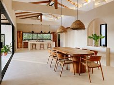 a dining room table and chairs in front of an open floor plan with exposed wood beams