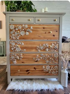 a wooden dresser with flowers painted on the front and drawers, along with white fur rugs