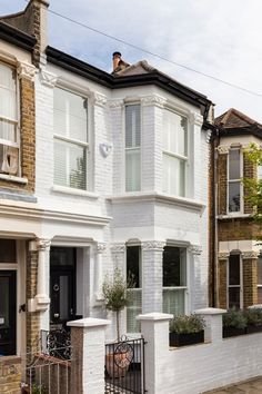 a white brick house with many windows and balconies on the front, along with an iron fence