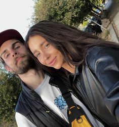 a man and woman taking a selfie with trees in the back ground behind them