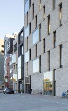 two bicycles are parked in front of a building with many windows and balconies