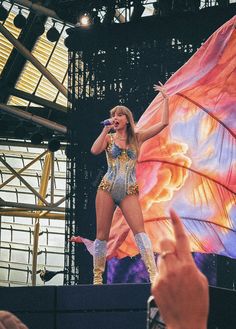 a woman is performing on stage with her hands in the air while holding a microphone