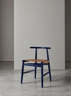 a blue chair sitting on top of a cement floor next to a white and gray wall