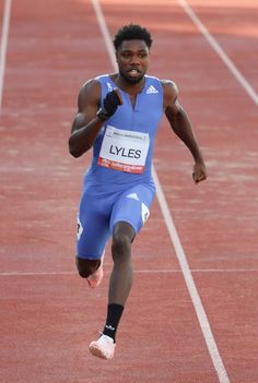 a man running on a track with his thumb up in the air while wearing blue