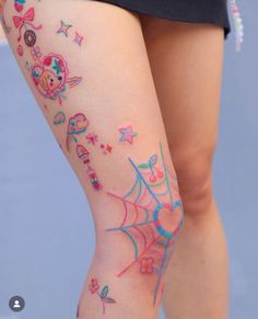 a woman's legs with colorful tattoos and spider webs on her leg,