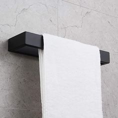 a white towel hanging on the side of a black wall mounted toilet paper dispenser