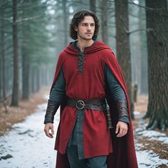 a man dressed in red and black is walking through the woods with his cape on