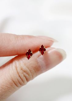 "Tiny diamond shaped stud earrings in a luxe ruby red - an everyday staple for the modern minimalist. Hand set faceted vintage Swarovski crystals. Hardware has been tumble polished for hours to achieve a satin finish, butterfly backings. Packaged in a beautiful gift box. Perfect for standard lobe piercings and small enough to be great stacking pieces for 2nd and 3rd piercings. MATERIALS [ stone ] vintage Swarovski crystal [ silver ] rhodium silver filled, sterling silver posts [ gold ] 14k gold Red Minimalist Jewelry With Birthstone, Minimalist Red Birthstone Jewelry, Dainty Birthstone Drop Earrings, Hypoallergenic 14k Gold Red Jewelry, Minimalist Birthstone Earrings, Dainty Red Earrings For Everyday, Minimalist 14k Gold Earrings With Gemstone, Dainty Tiny Red Jewelry, Dainty 14k Gold Gemstone Earrings