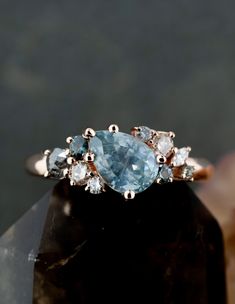 a close up view of an aqua and white diamond ring on top of a rock