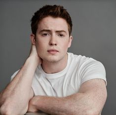 a young man sitting at a table with his hand on his head and looking off to the side