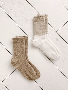 two pairs of socks sitting on top of a white wooden floor next to each other