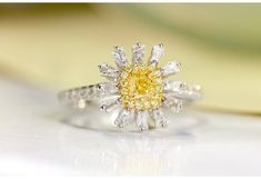 a yellow and white diamond ring sitting on top of a table