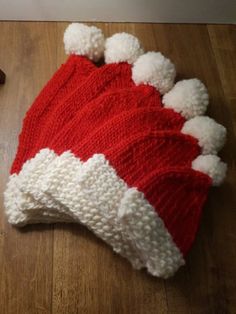 a red and white knitted hat laying on top of a wooden floor next to a dog toy