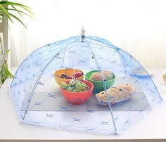 a clear umbrella sitting on top of a table filled with bowls of fruit and muffins