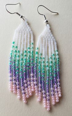 two pairs of beaded earrings with white, purple and green beads hanging from them