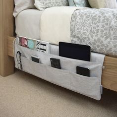 a bed with an attached storage pocket on the bottom and two phone holders in it