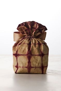 a tie dyed bag sitting on top of a white table next to a brown ribbon