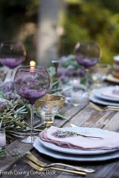 the table is set with plates, glasses and candles for an elegant dinner or party