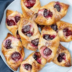 small pastries are arranged on a plate with powdered sugar and jelly toppings