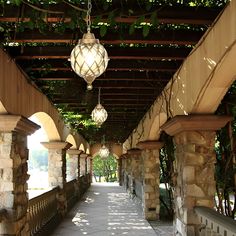 the walkway is lined with stone pillars and lanterns hanging from it's ceilings