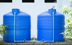 two large blue water tanks sitting next to each other in front of a white building