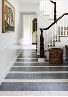 a hallway with blue and white tile flooring next to a bannister on the wall