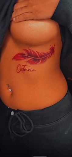 a woman's stomach with a red feather tattoo on her belly and the word future written in cursive writing