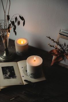 two lit candles sitting on top of an open book