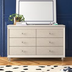 a dresser with a mirror on top of it in front of a blue painted wall