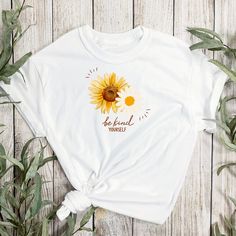 a white t - shirt with the words be kind to yourself on it and a sunflower