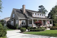 the house is made of wood and has white trim on the front porch, along with two story windows